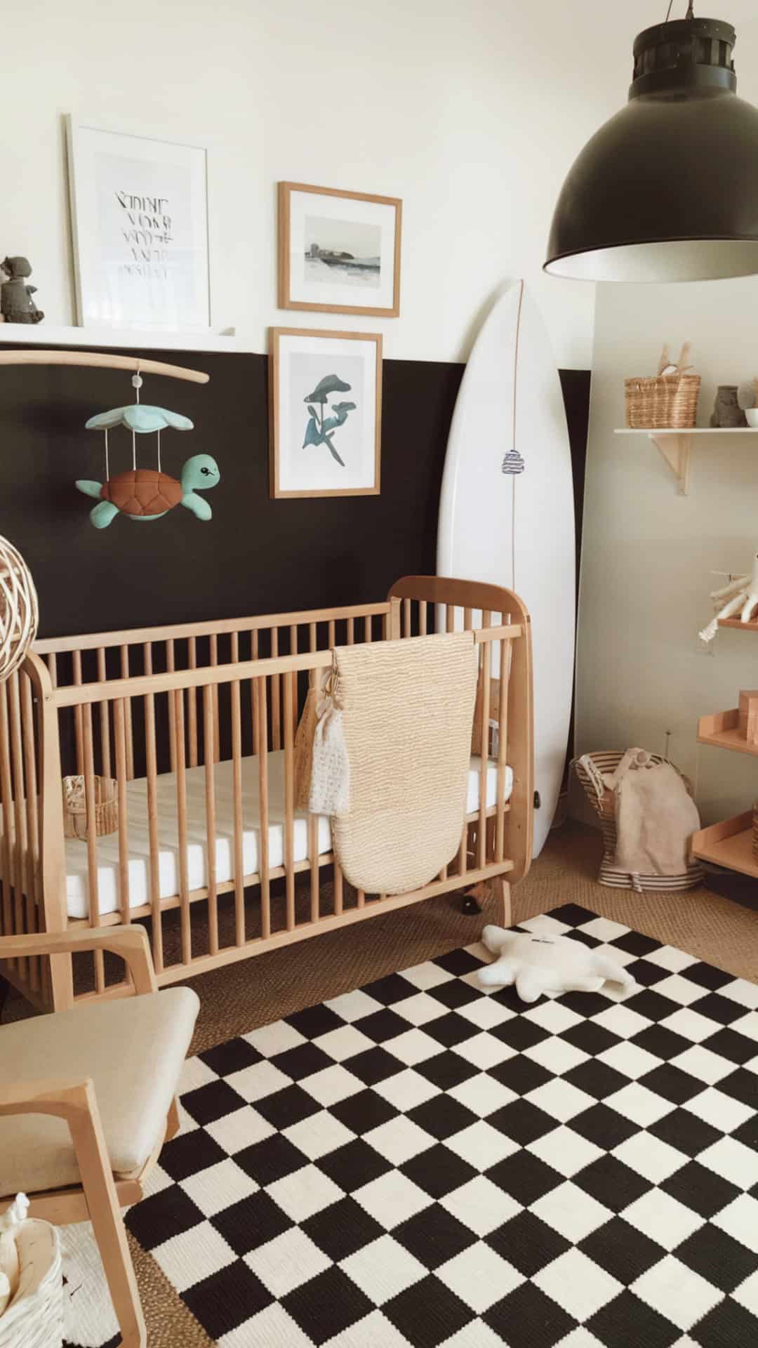 Surf-inspired nursery with a black-and-white checkered rug, wood crib, coastal decor, and a modern, adventurous vibe.