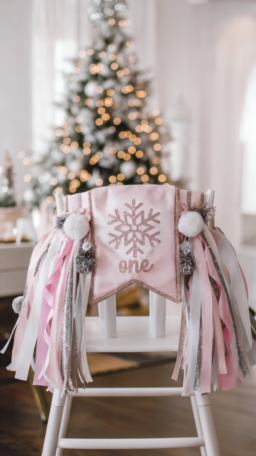 Highchair with pink and glittery snowflake banner and ribbon decorations for a Winter ONEderland birthday party.