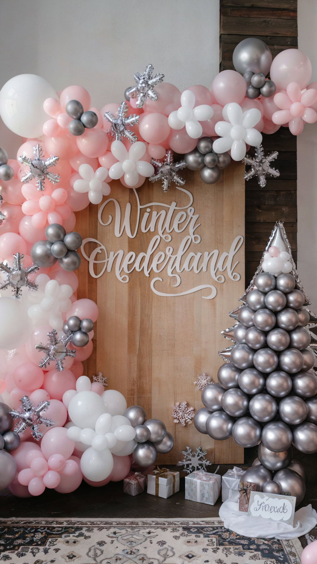 Winter ONEderland backdrop with pink, white, and silver balloon garlands, metallic snowflakes, and a balloon Christmas tree.